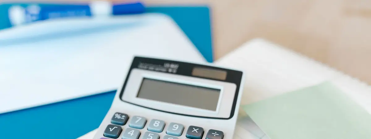 A desk calculator resting on paperwork and a blue folder