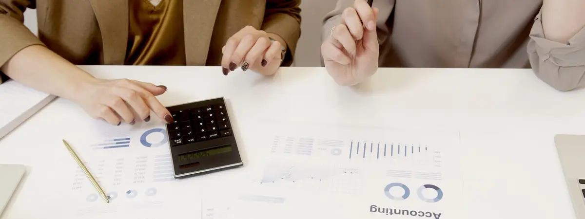 Two colleagues going through printed financial statements with a calculator