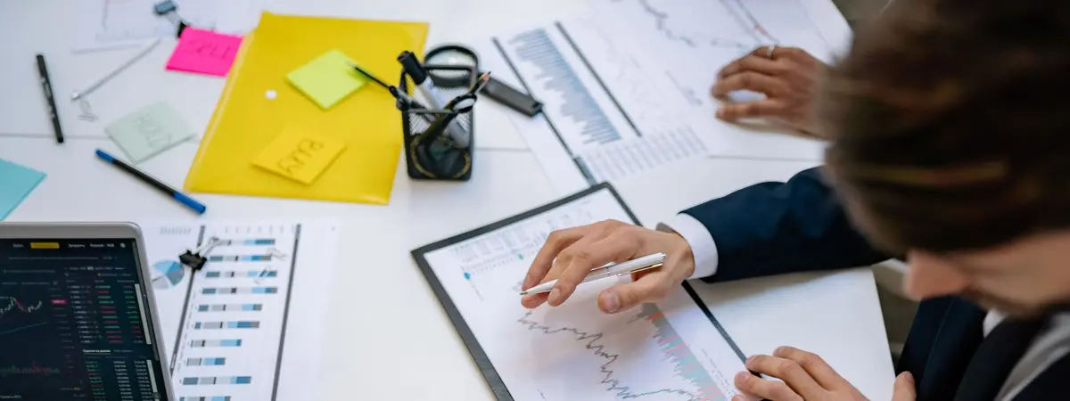 Colleagues marking up printed charts beside sticky notes on a desk