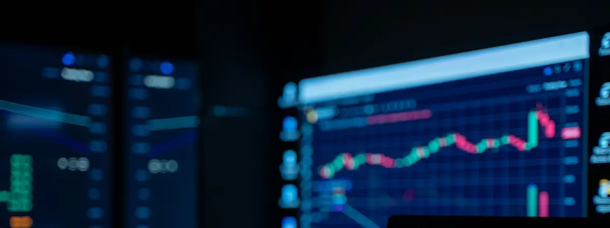 Monitors showing stock market charts in a dim room