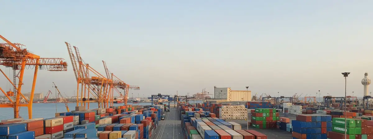 Cargo containers stacked at a harbor at sunrise