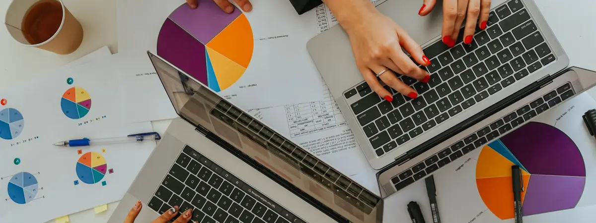 A team comparing printed charts and laptops at a meeting table